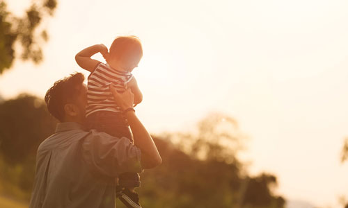 Young boy on dad's shoulders outside